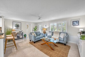 A living room with a grey sofa set, a coffee table, and a dining area with a chair and table.