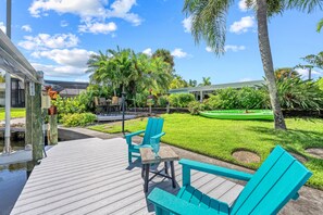 A wooden deck with outdoor furniture, a grassy lawn, and a green kayak. - La Contento Casa | Private Heated Pool, Pet Friendly, Walk to Siesta Key Village and Beach (Siesta Key)