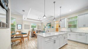 A spacious kitchen with white cabinets, a large island, and a dining area with a wooden table and chairs.