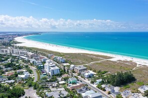 Vista aérea de un pueblo costero con playa, edificios y caminos.