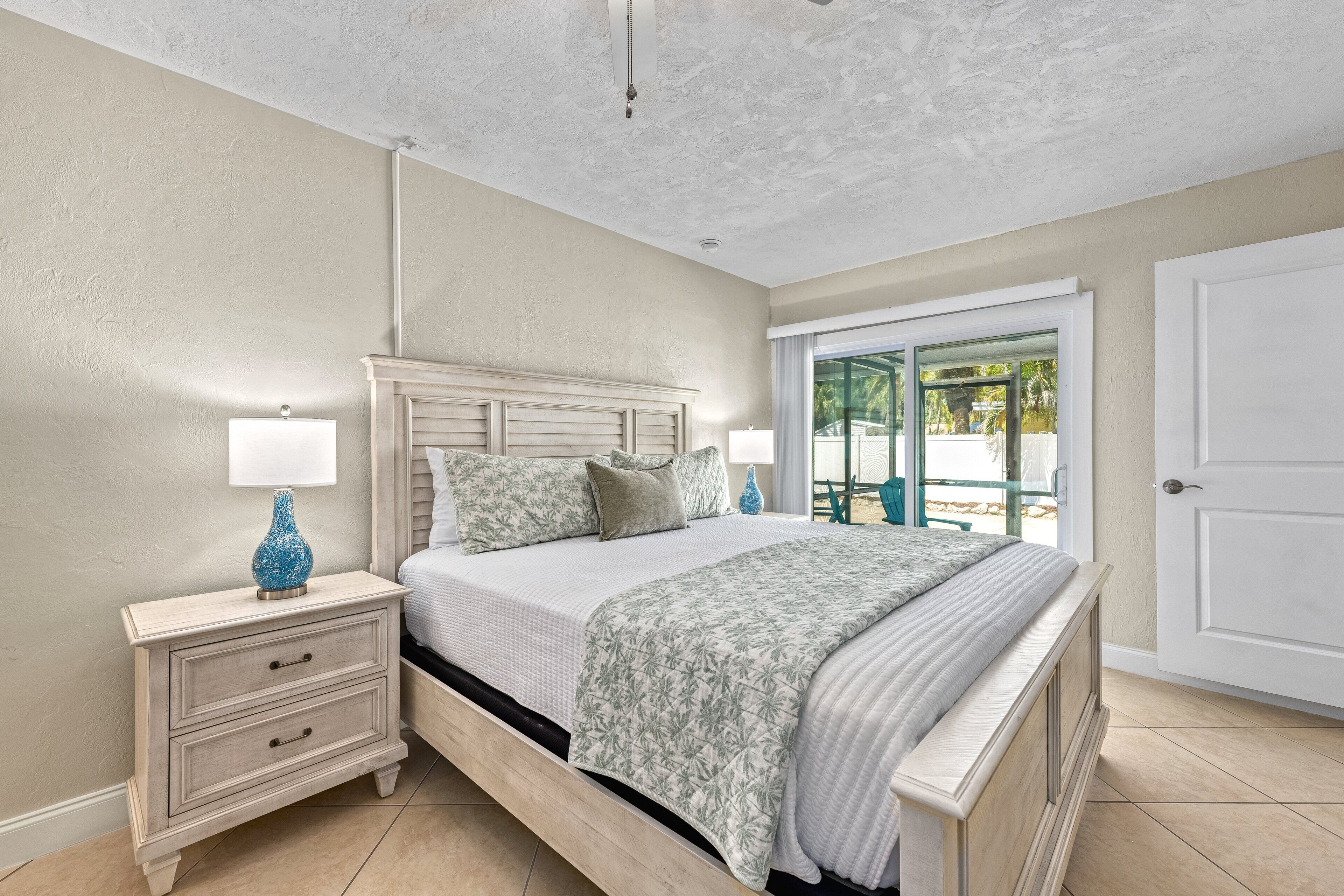 A bedroom with a bed, nightstands, and a door to a balcony.