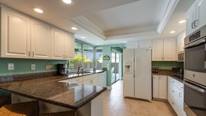 A modern kitchen with white cabinets, granite countertops, and stainless steel appliances. - Villa De Paradisio | Waterfront Home w/ Private Pool, Fishing Dock, Close to Beach & Village! (Siesta Key)