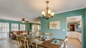 A dining area with a wooden table set for four, surrounded by chairs. There is a ceiling fan above the table and a chandelier hanging from the ceiling. - Villa De Paradisio | Waterfront Home w/ Private Pool, Fishing Dock, Close to Beach & Village! (Siesta Key)
