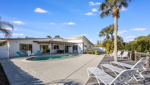 A modern house with a swimming pool, outdoor seating, and a wooden deck. - Villa De Paradisio | Waterfront Home w/ Private Pool, Fishing Dock, Close to Beach & Village! (Siesta Key)