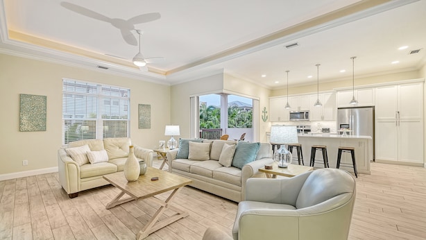 A spacious living room with a beige sofa, a coffee table, and a ceiling fan.