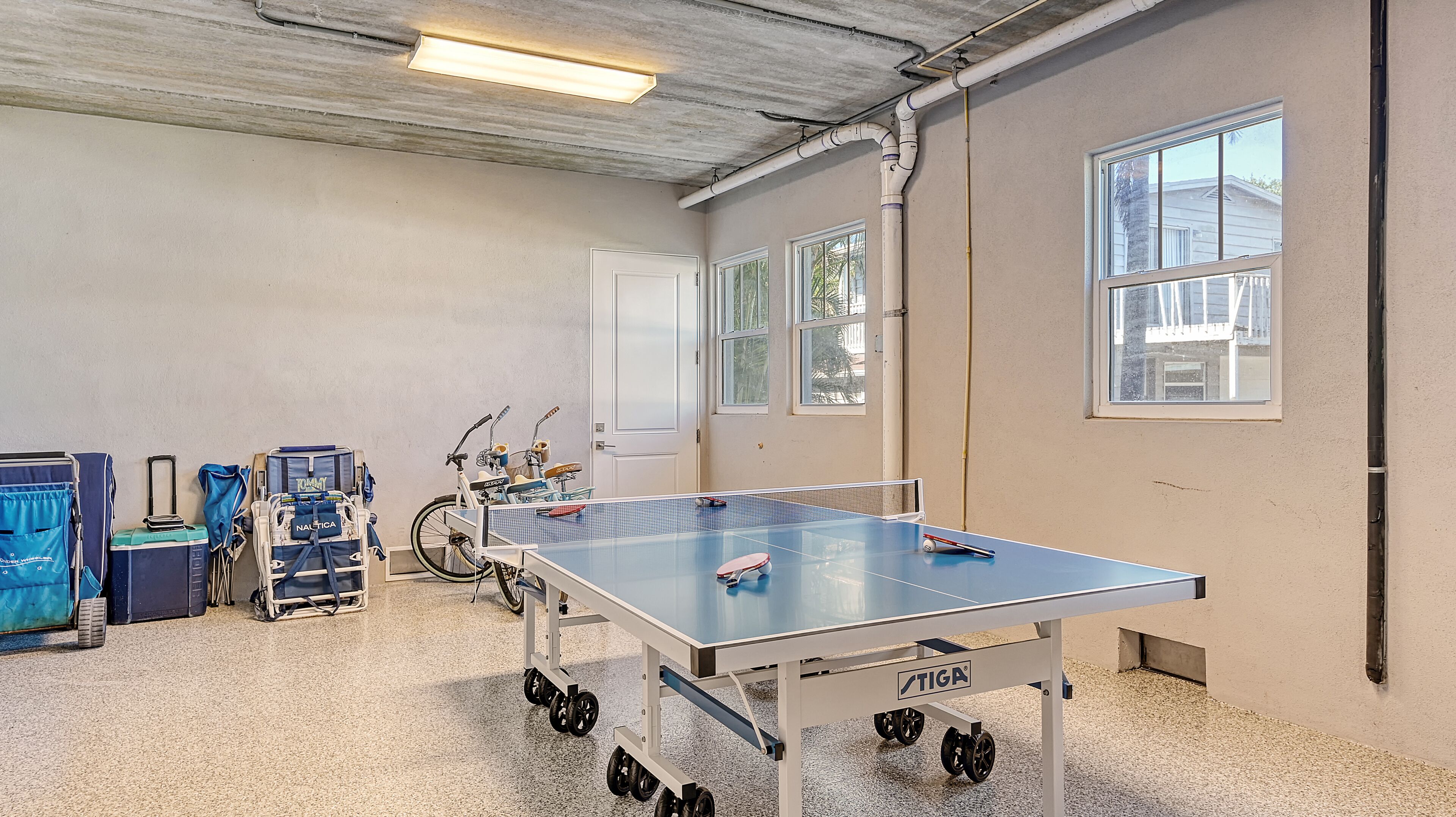 A spacious room with a ping pong table, a wheelchair, and a bicycle.