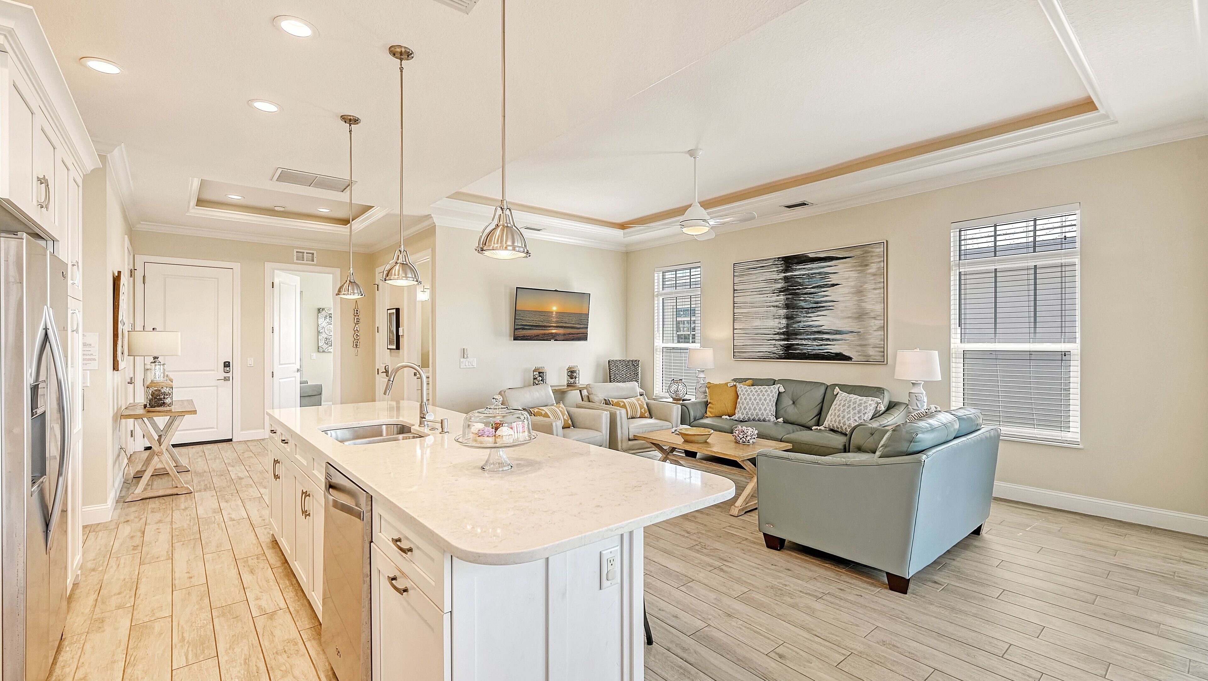 A spacious kitchen with a central island, a dining area with a sofa, and a living room with a large window.