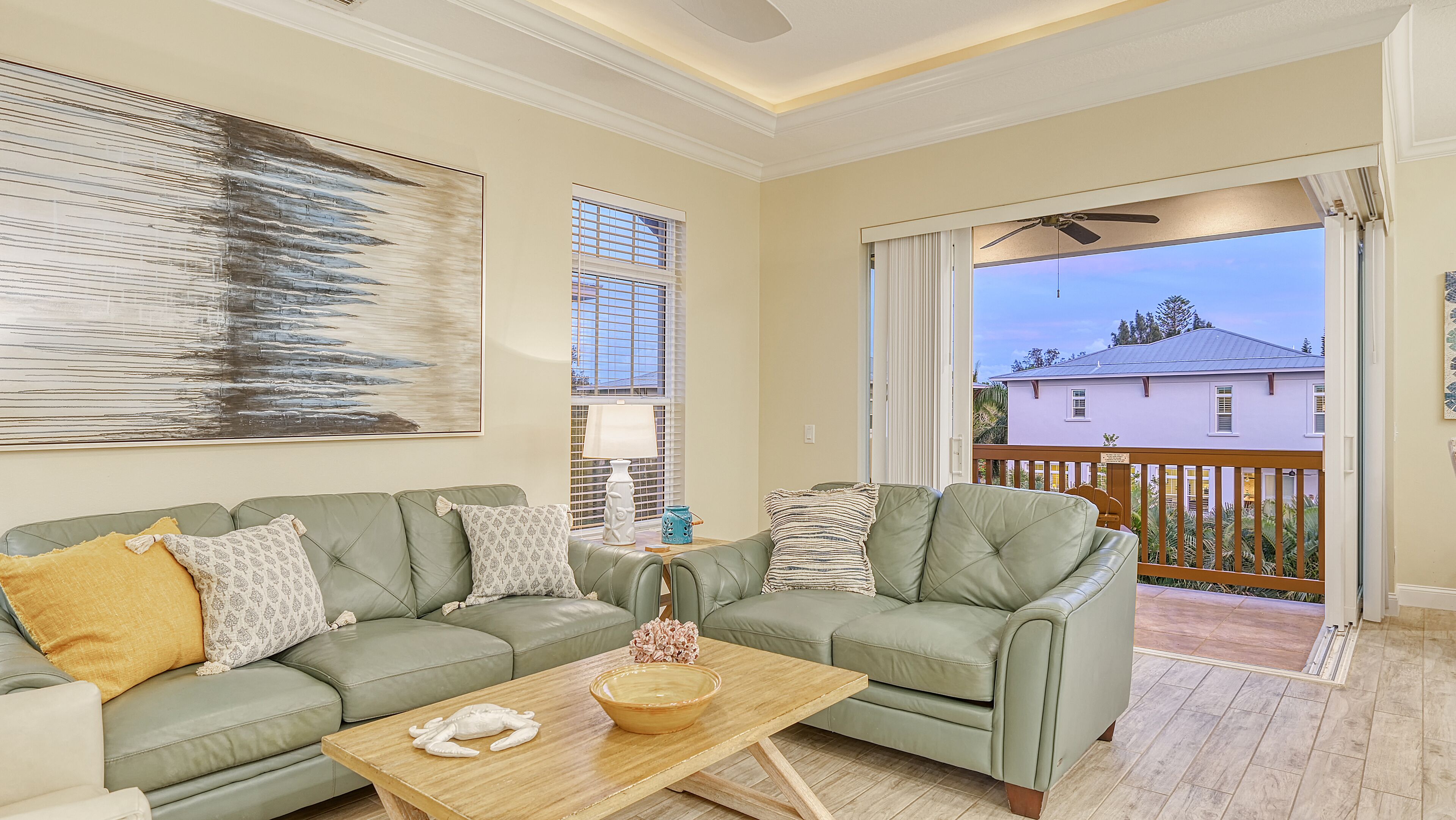 A living room with a green sofa set, a wooden coffee table, and a large abstract painting.