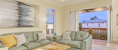 A living room with a green sofa set, a wooden coffee table, and a large abstract painting.