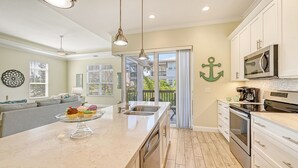Ett modernt kök med en central köksö, vitvaror i rostfritt stål och utsikt mot omgivningen.