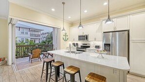 Ett modernt kök med en stor köksö, rostfria vitvaror och utsikt över en bostadsbyggnad.