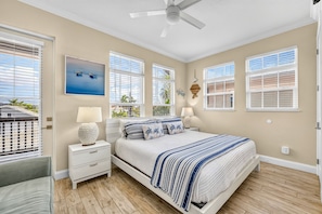 A bedroom with a bed, nightstands, a ceiling fan, and windows with blinds.