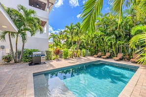 A swimming pool with lounge chairs, a barbecue grill, and tropical plants. - The Abalone | Two Heated Pools, Dual-Unit Duplex, Steps to Crescent Beach & Point of Rocks (Sarasota)