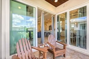 A spacious balcony with two wooden chairs and a table, overlooking a residential area.
