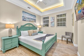 Une chambre à coucher avec un lit, des tables de chevet, une chaise et des œuvres d’art accrochées aux murs.