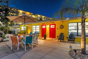A hotel exterior at night with a starry sky, a yellow building, red doors, outdoor seating with chairs, and a palm tree. - 🌴 Sol Y Mar | Private Duplex - Two Casitas, Walk to Siesta Keys Crescent Beach, HOA Pool (Siesta Key)