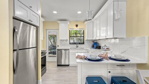A modern kitchen with white cabinets, stainless steel appliances, and a marble countertop. - 🌴 Sol Y Mar | Private Duplex - Two Casitas, Walk to Siesta Keys Crescent Beach, HOA Pool (Siesta Key)