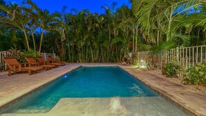 A rectangular swimming pool with clear blue water, surrounded by a tiled deck and wooden lounge chairs. - Casa Eulimia | Pet Friendly, Ping Pong Table, Private Heated Pool, Steps to Beach! (Sarasota)