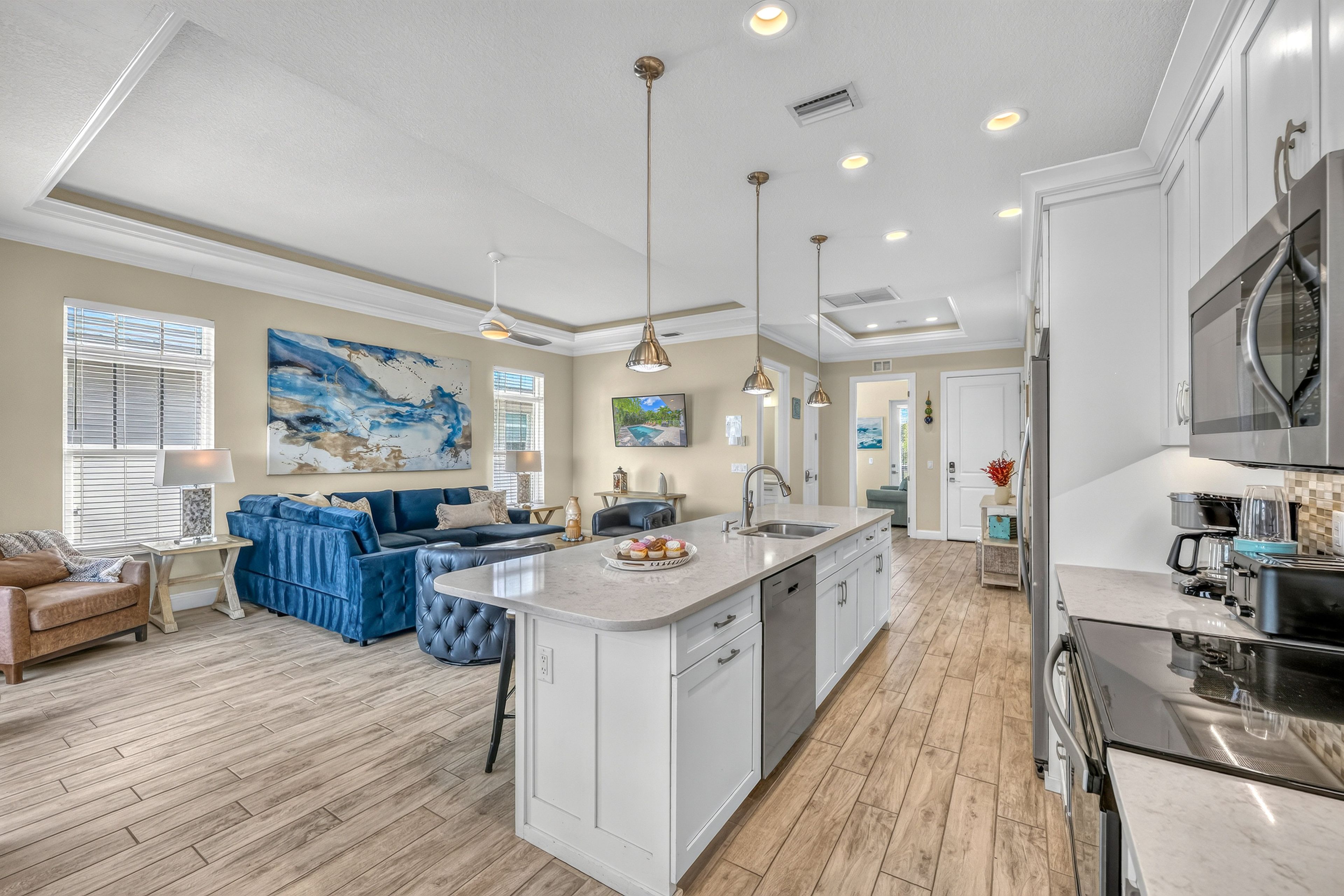 A modern kitchen with a central island, stainless steel appliances, and pendant lighting.