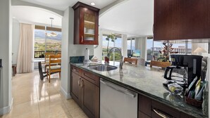 A modern kitchen with a large island, dark wood cabinets, and a view of the mountains.