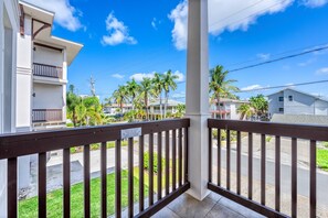 Un balcón con vista a una calle residencial, palmeras y casas.