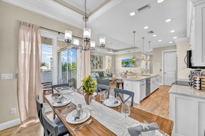 A spacious dining area with a large table set for six, a chandelier, and a view of the outdoors. - Casa Junonia | Heated Pool, Private Cabana Lounge, Steps to Crescent Beach & Point of Rocks (Sarasota)