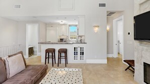 Une cuisine moderne avec des meubles blancs, un îlot central doté de tabourets et une cuisinière intégrée.