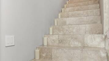 Un escalier recouvert de carreaux de couleur beige et agrémenté d’appliques murales blanches.