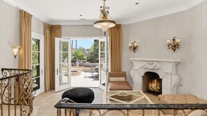 Amplia sala de estar con chimenea, balcón con cortinas y un candelabro.