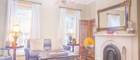 A traditional living room with a fireplace, a chandelier, and a large mirror.