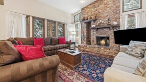 A cozy living room with a brick fireplace, large windows, and a comfortable seating area.