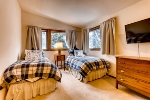 A bedroom with two beds, a nightstand, a dresser, and a TV. - Private Home on Vail Mountain | 324W Beaver Dam (Vail)