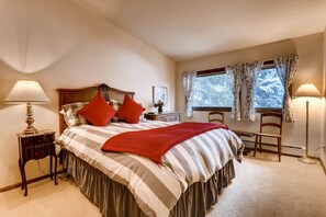 Cozy retreat with a large bed, nightstand, and desk, featuring a striped bedding set and a throw blanket.