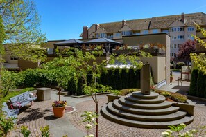 Ein Innenhof mit einer zentralen Fontäne, einer Bank und einem Blumentopf.