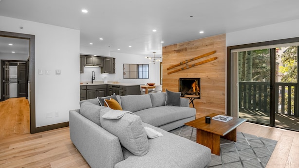 A modern living room with a grey sectional sofa, a wooden coffee table, and a fireplace.
