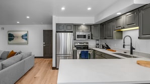 A modern kitchen with grey cabinets, stainless steel appliances, and a white countertop.