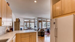 A modern kitchen with wooden cabinets, a central island, and a large refrigerator. - Views, Bright Spacious Vail Villa, SAV4B (Vail)