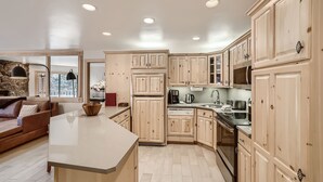 A spacious kitchen with wooden cabinets, a central island, and a stone accent wall. - Vail Platinum Condo in Lionshead Village W307 (Vail)