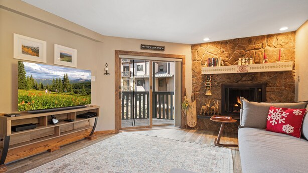 Una sala de estar con televisión, chimenea, sofá y pared de piedra.