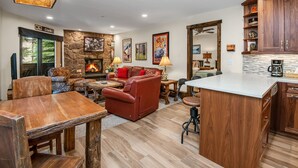 Un salon spacieux doté d’une cheminée, d’un mur en pierre décorative et d’un coin salon confortable.