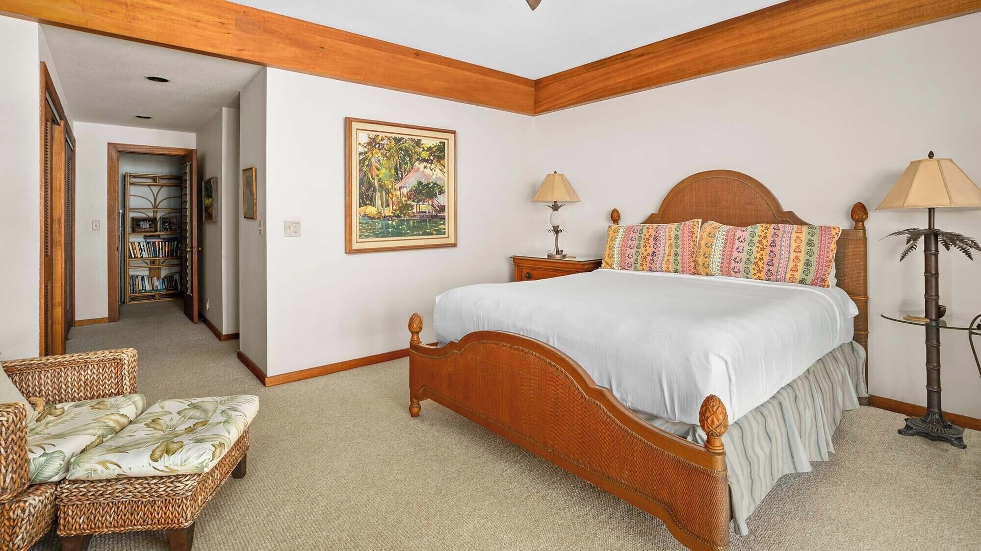 Une chambre à coucher avec un lit en bois, deux tables de chevet, une chaise, une bibliothèque et un tableau encadré au mur.