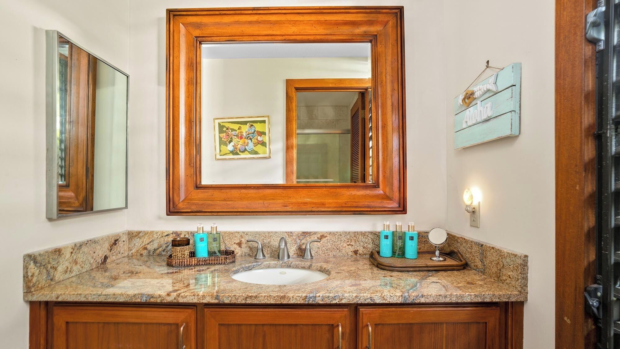 Un baño con tocador de madera, un espejo grande y encimera de granito.