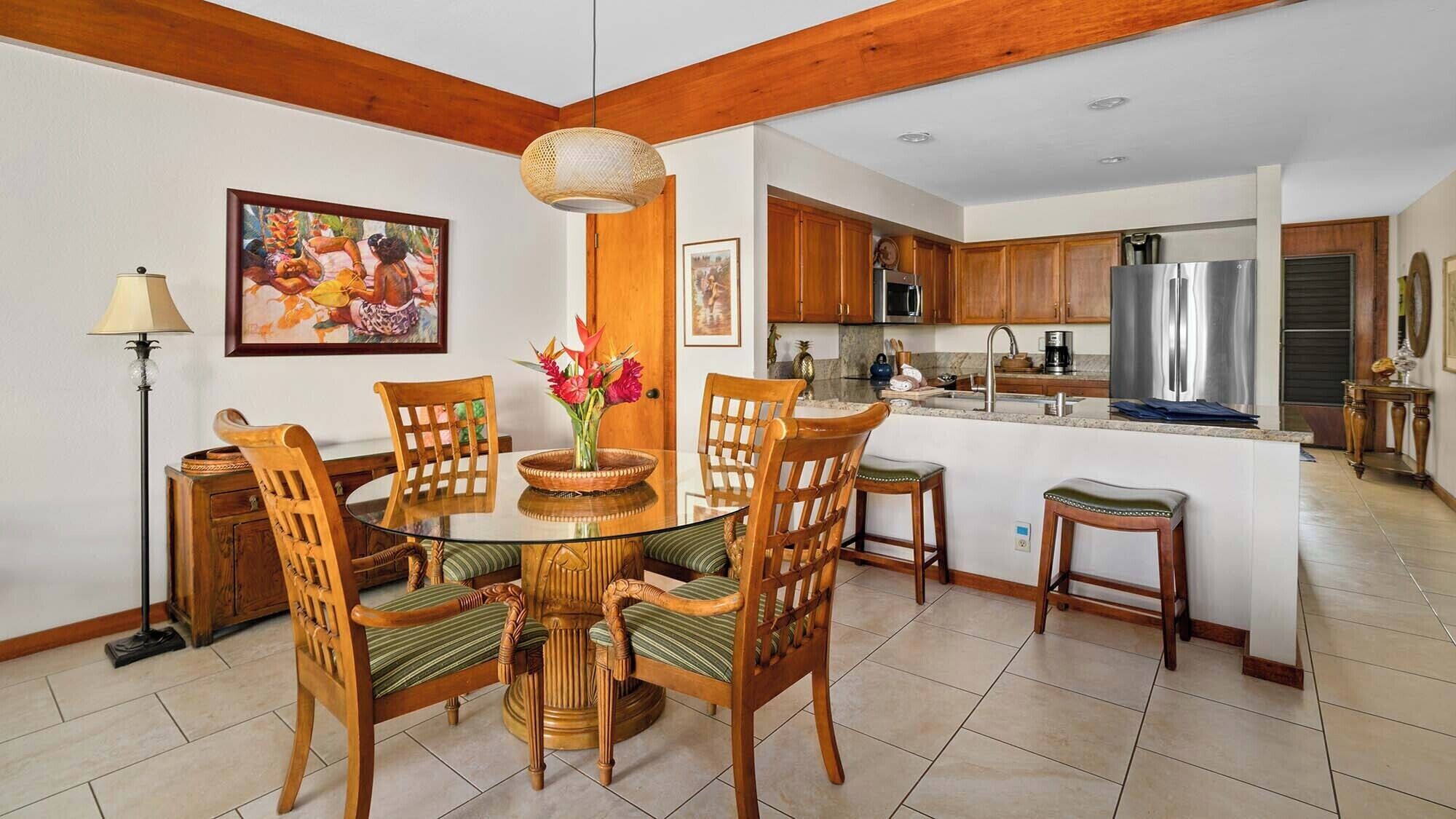 A dining area with a glass table surrounded by wooden chairs with cushioned seats.