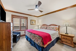 A bedroom with a bed, bedside tables, a ceiling fan, a window, and a TV. - Remodeled Condo Vail Mtn Views | W201 (Vail)