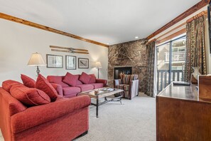 A living room with a red sofa, a coffee table, and a fireplace. - Remodeled Condo Vail Mtn Views | W201 (Vail)