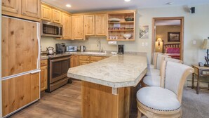 A kitchen with wooden cabinets, a granite countertop, a refrigerator, a microwave, a stove, and a sink. - Vail Mtn Views, Pool, Hot Tub - Great Mountain feel and beautiful Kitchen. (Vail)