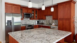 Una cocina moderna con armarios de madera, electrodomésticos de acero inoxidable y una isla grande de granito.