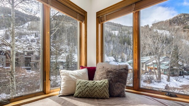 Canto de um quarto com grandes janelas dando para uma paisagem nevada.