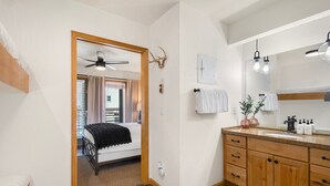 Um banheiro com armários de madeira, um espelho, um ventilador de teto e uma decoração com chifres de veado.