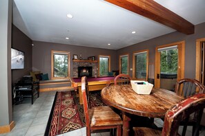 Une pièce chaleureuse avec une cheminée, une table de billard et une table à manger avec des chaises.